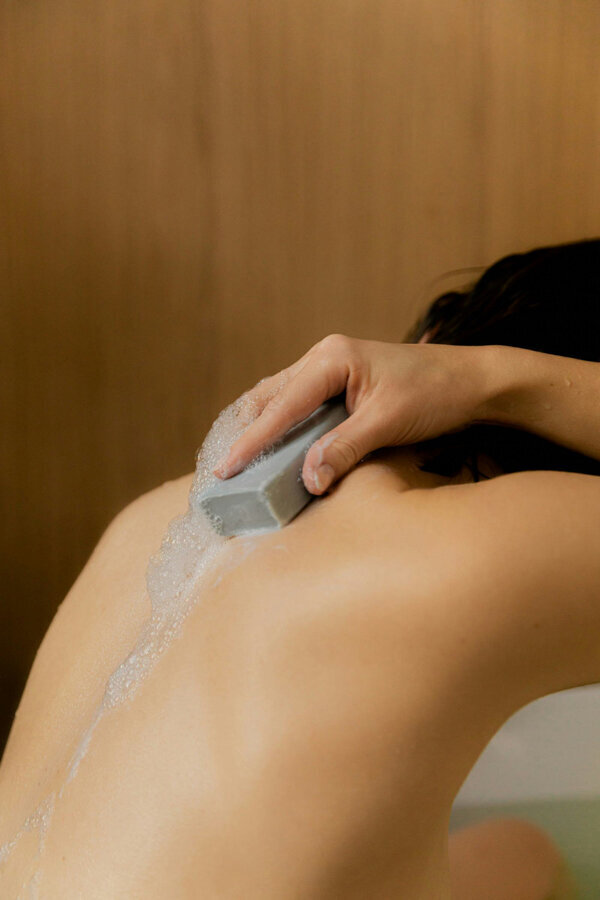 person washing back with bar soap