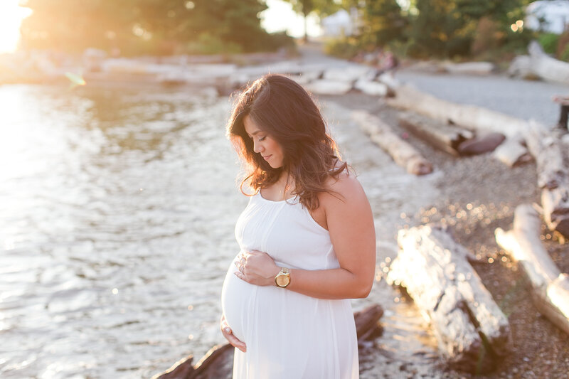 Pregnant woman in white dress holding stomach