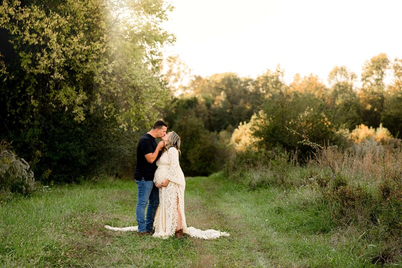 charlotte expectant couple embraces in a kiss while standing in a field