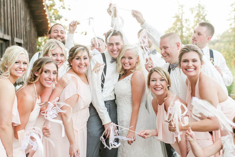 Bridal party holding streamers smiling at camera