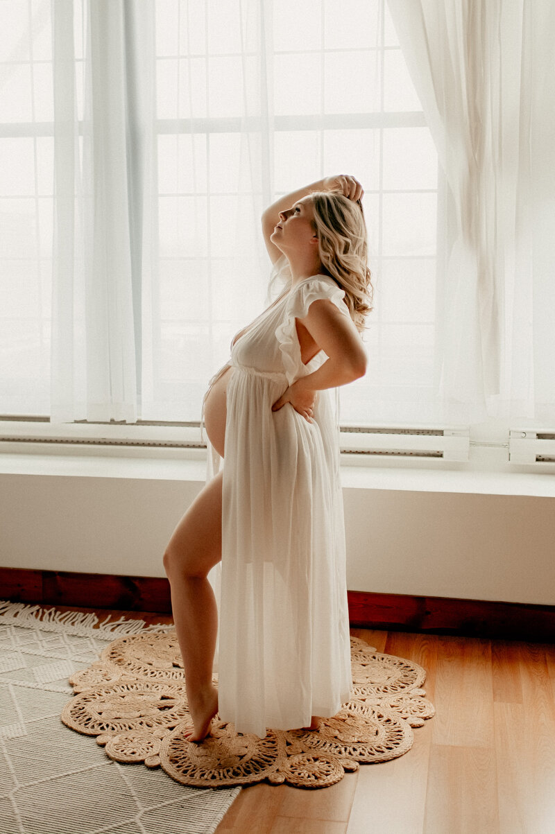 pregnant woman in sheer gown posing to show belly