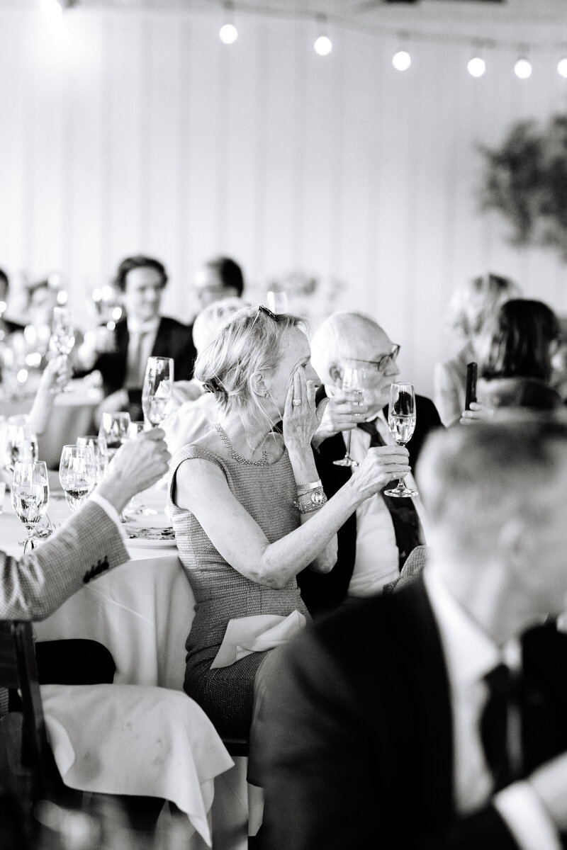 black and white shot of family members tearing up at wedding reception.