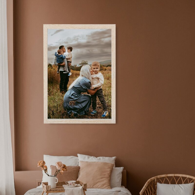 A beautiful tan colored bedroom  with a portrait of a family  in a field on the wall