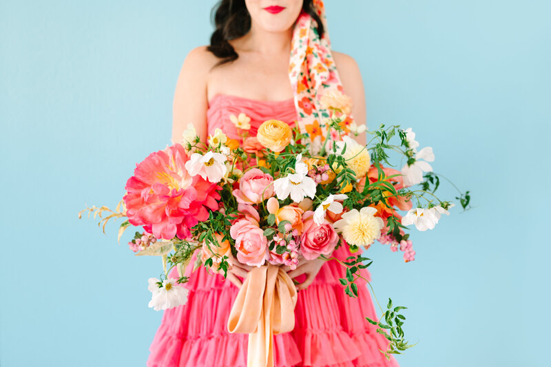 woman in pink vintage dress holding colorful bouquet of flowers
