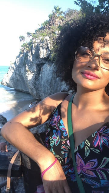 A woman with curly hair and glasses outside