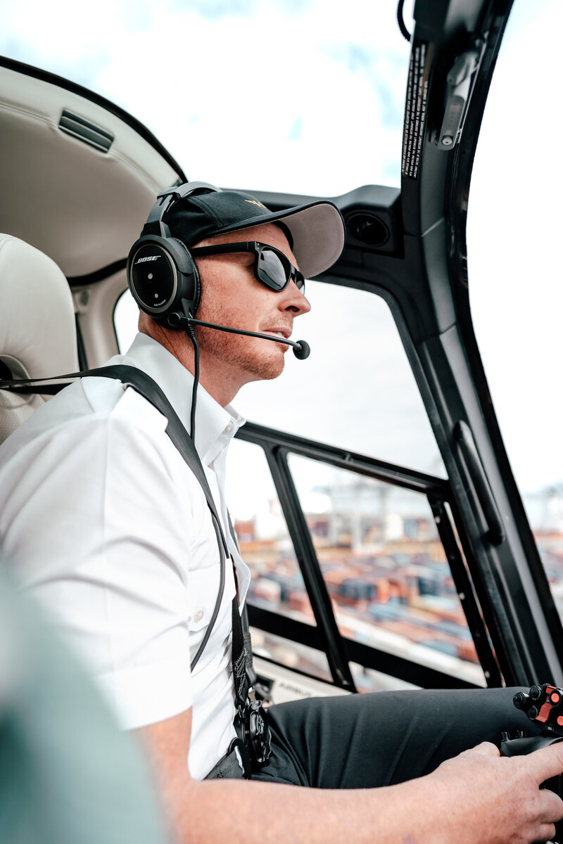 Close up of a male pilot inside the helicopter flying the helicopter over Auckland City captured by Auckland Commercial Photographer Zanthe Vorsatz