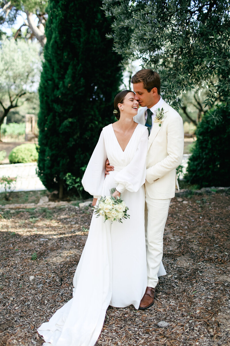 groom-kisses-bride-under-olive-tree-at-luxury-wedding-at-chateau-rasque