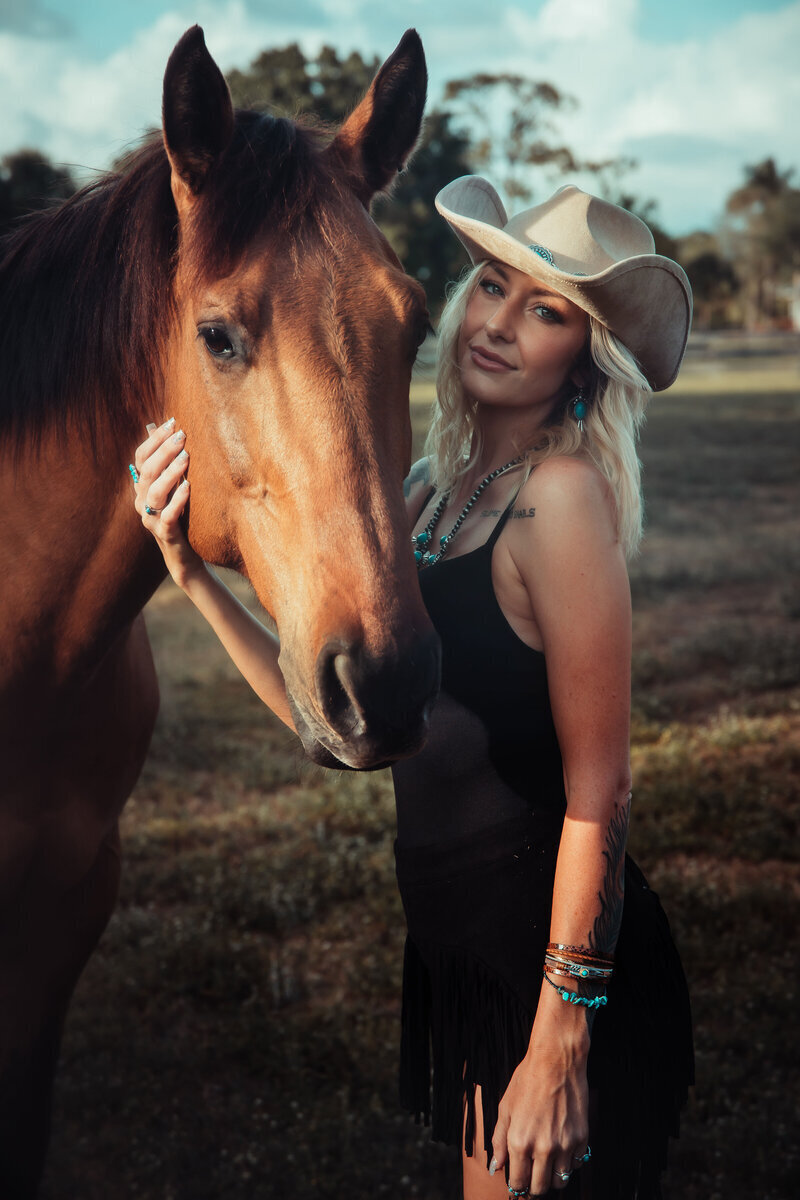 Woman posed with cowboy hat, black fringe dress, with a vintage style
