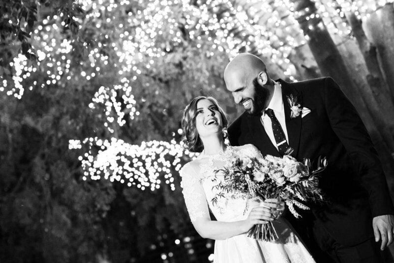 Bride and Groom laughs under sparkling tree lights