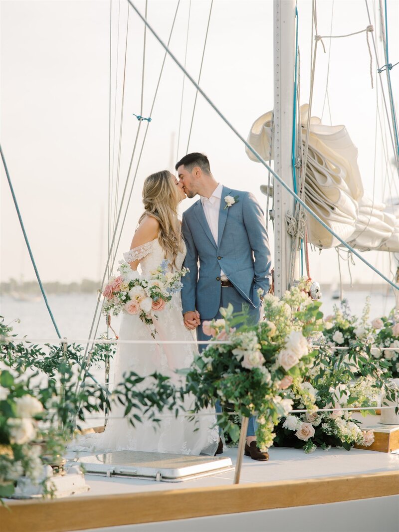 A bride and groom kissing on a private sailboat