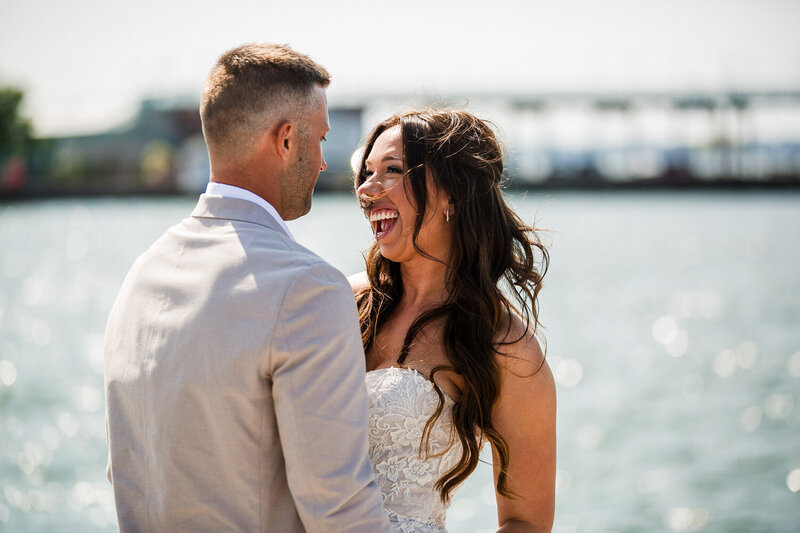 Bride smiling at groom next to water on Dobbins Landing in Erie PA