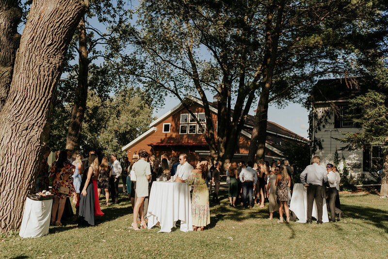 guests gather for cocktail hour outside the barn at barnwood events, a wedding venue in madison, winconsin.