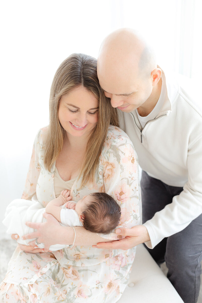 new mom and dad hold their baby girl as she sleeps