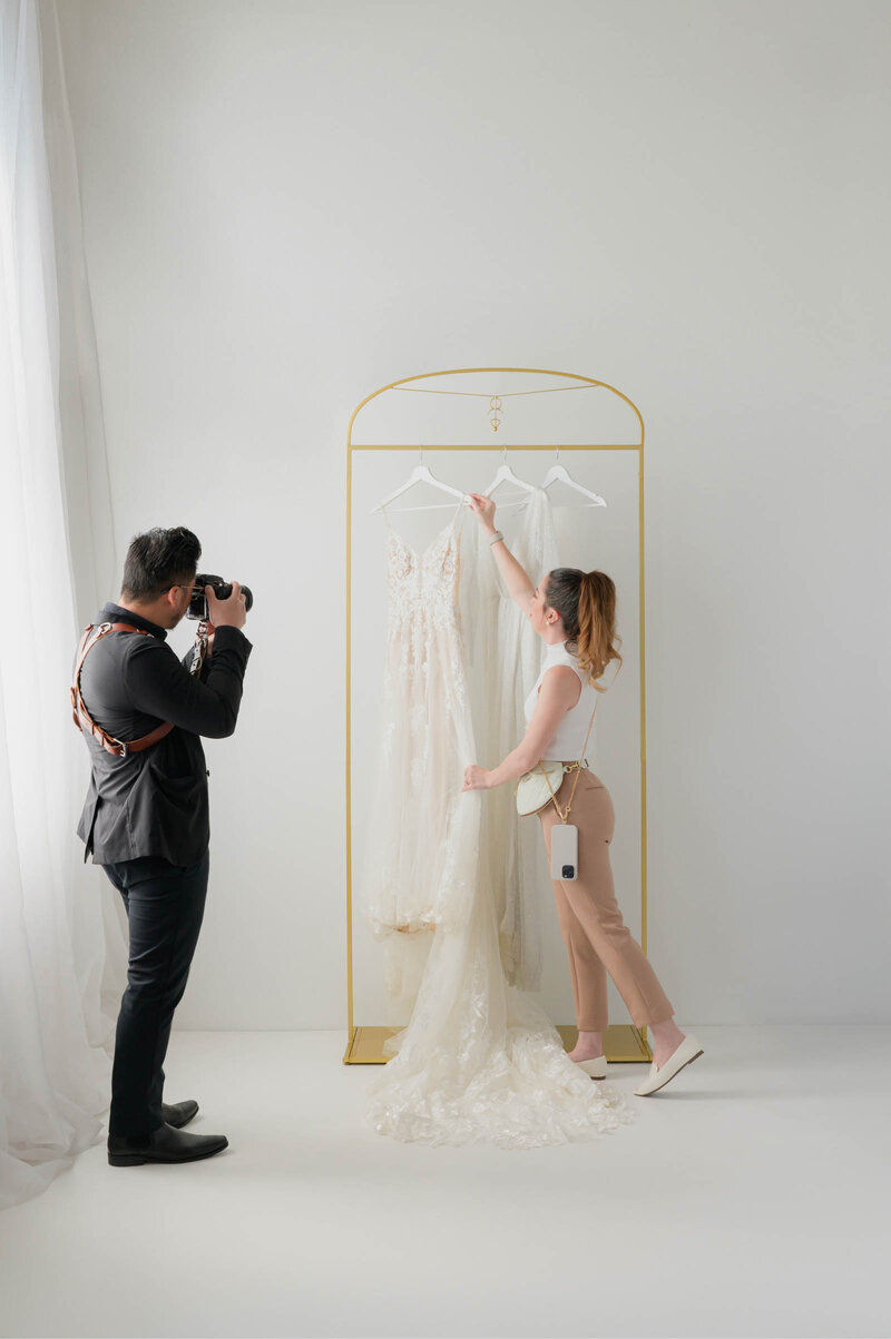 kaylyn leighton styling wedding dresses with steamer in seamless photography studio.