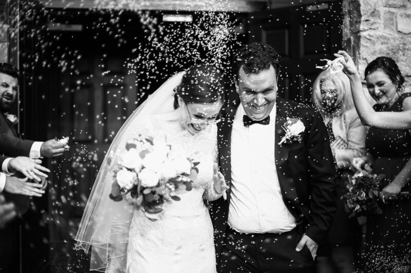 Bride and groom exit church amidst a shower of rice thrown by their guests  at Greek Orthodox church in Erie PA