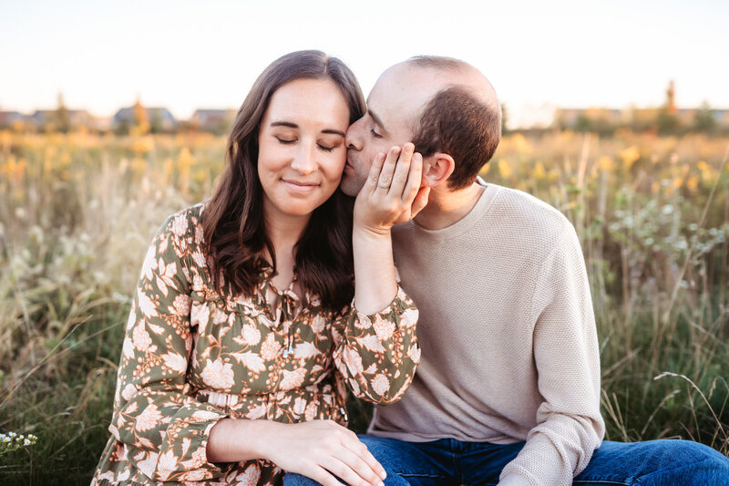 Man kissing pregnant wife in meadow