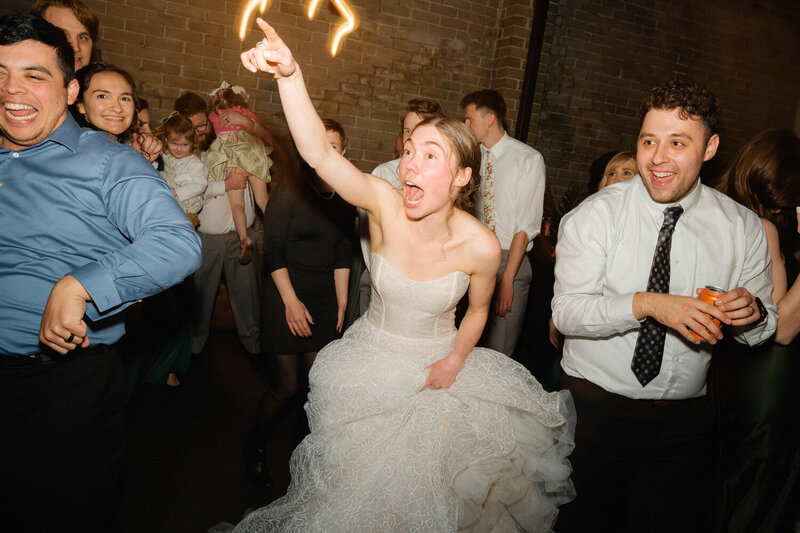 Bride points her finger amidst a crowded dance floor