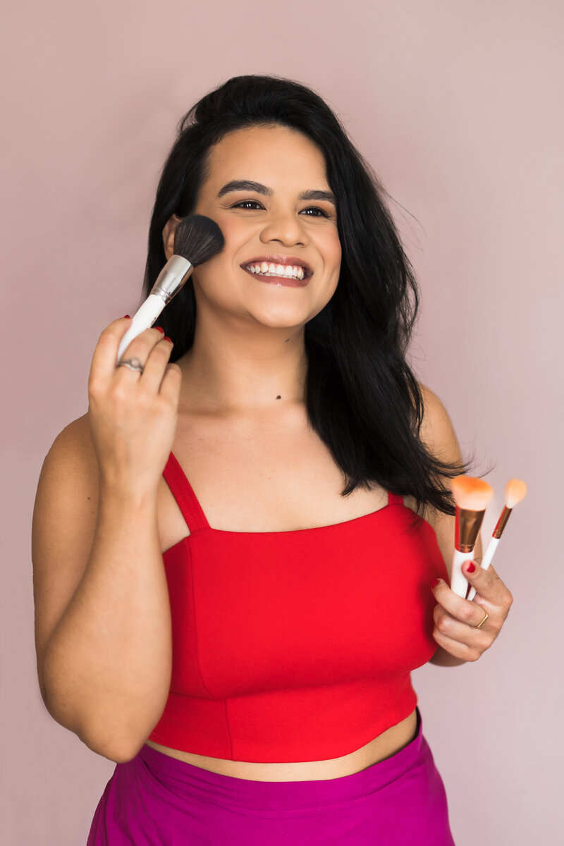 brand photo of a Make Up Artist touching her face with makeup brushes