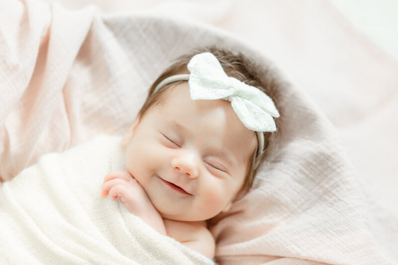 Ann Arbor Newborn Photographer captures smiling baby girl swaddled in basket
