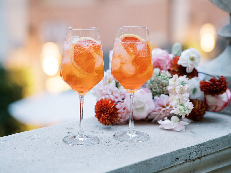 A photo of Aperol Spritz during an editorial wedding. This is styled with flowers in the background.