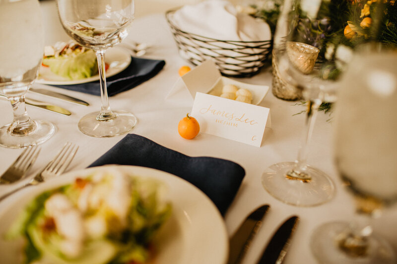 Tented paper place cards with gold calligraphy and guest pronouns