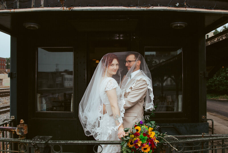 bride and groom smiling under veil