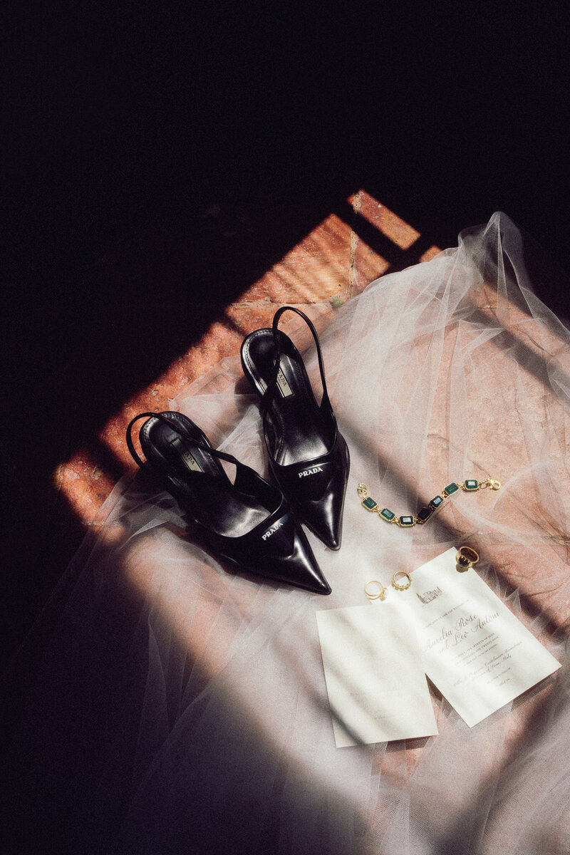 Cinematic flatlay of black bridal heels, jewellery, and wedding details in soft dramatic light, captured by a luxury documentary wedding photographer UK.