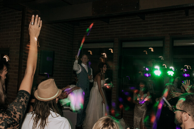 groom throwing flashing light up glow sticks to wedding reception guests