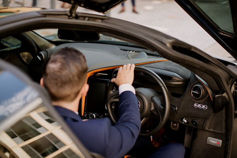Groom inside the sports car holding the steering wheel