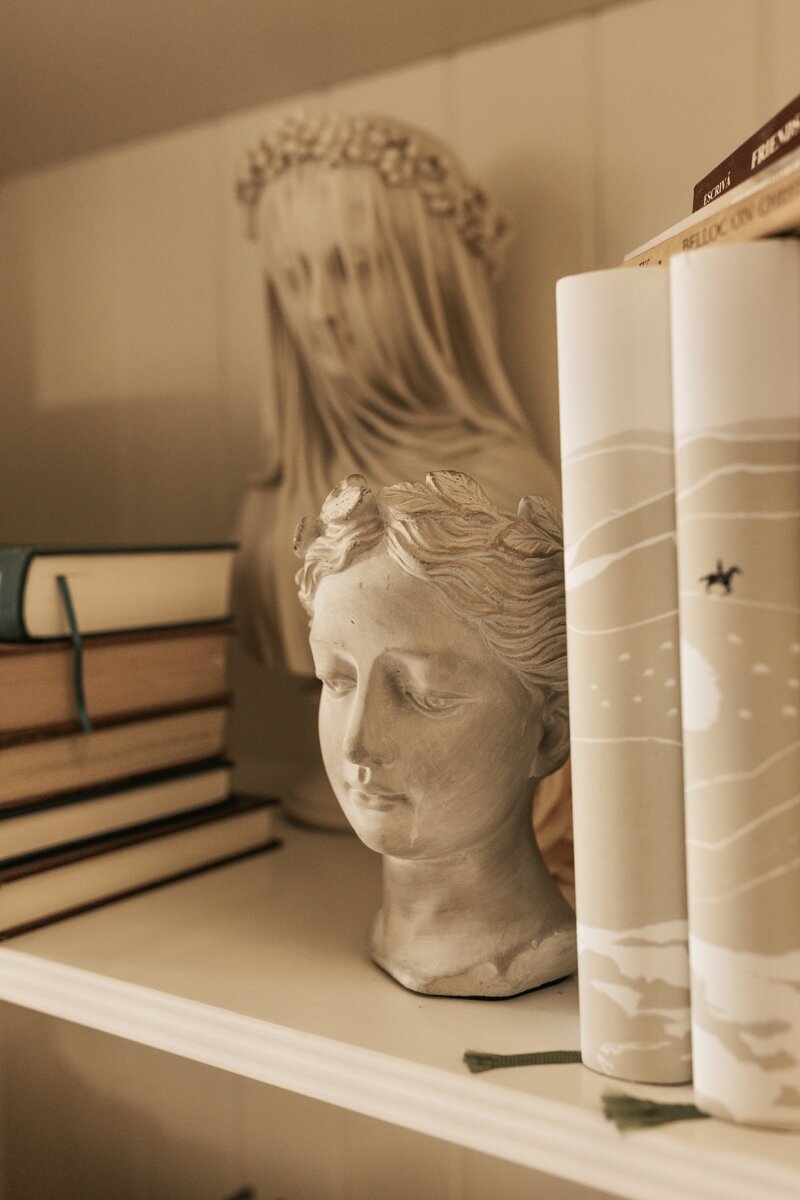 a stone bust on a bookshelf