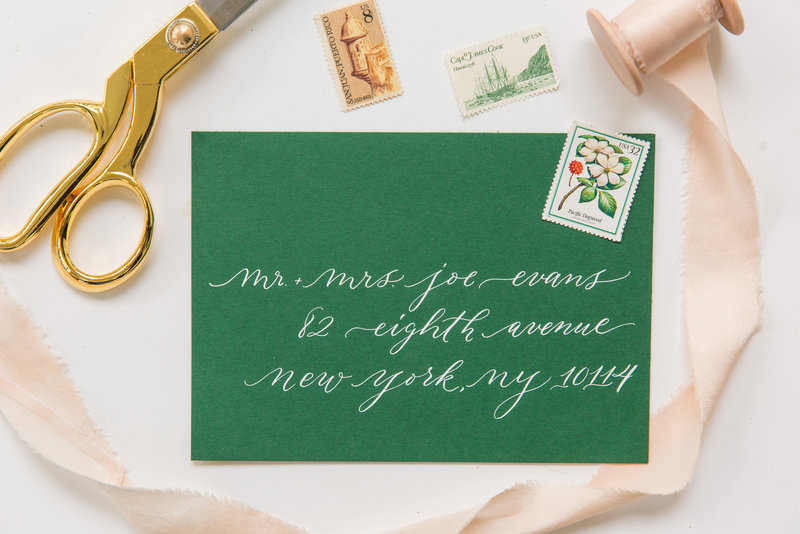 Airy and romantic white ink calligraphy on a green wedding envelope by Lewes Lettering Co