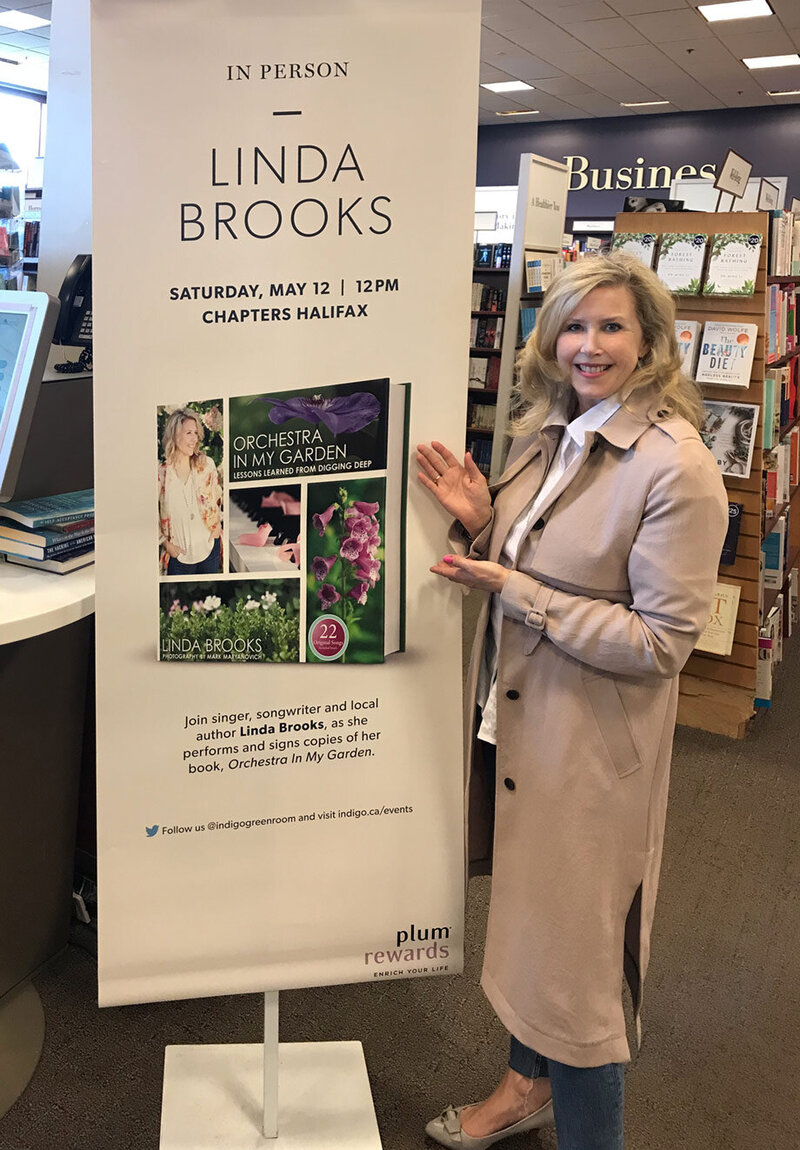 Marketing materials image Author Linda Brooks beside Chapters in store display Book Signing Orchestra In My Garden