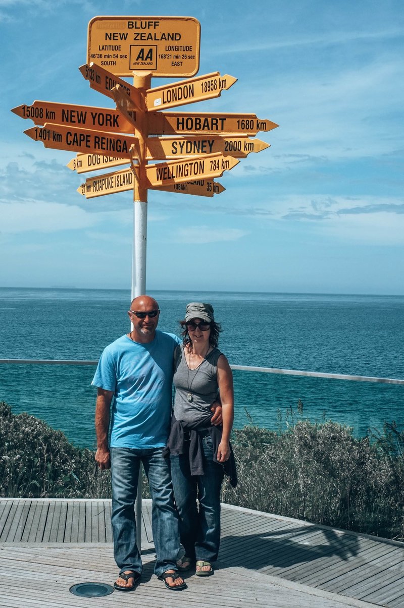 Lynda and Warren standing in front of iconic sitrling point signpost at Bluff, New Zealand