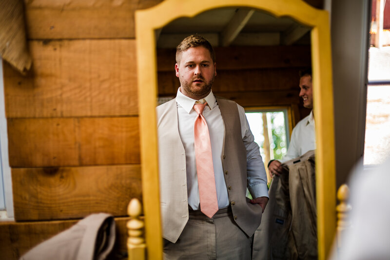 Groom looks in mirror while getting ready at Port Farms