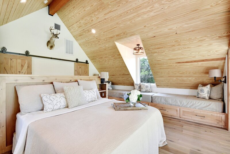 A frame bedroom with bed with beige duvet and wood panel ceilings