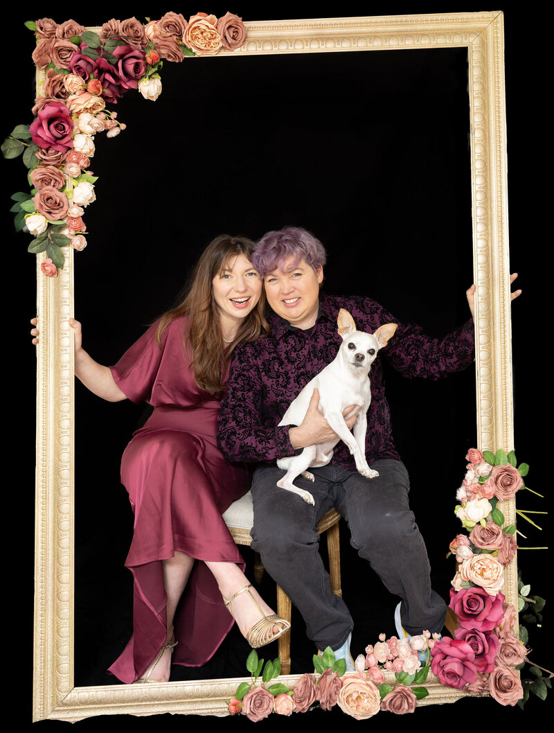 A couple with their dog sitting in a large picture frame