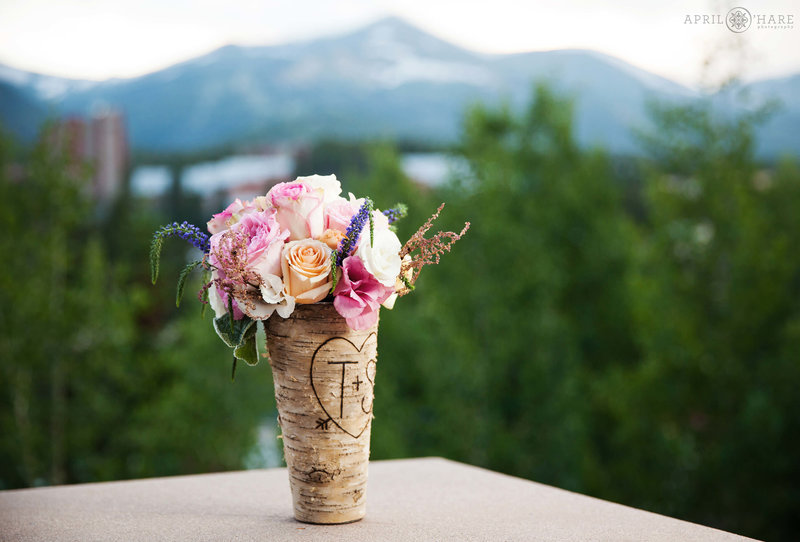 Pink flower bouquet in a faux aspen bark covered vase on the outdoor deck area at Main Street Station in Breckenridge