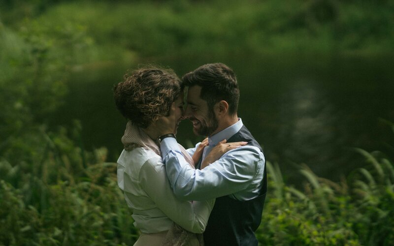 Romantic moment of a couple hugging and gazing deeply into each other's eyes, capturing an intimate connection and love in a serene outdoor setting