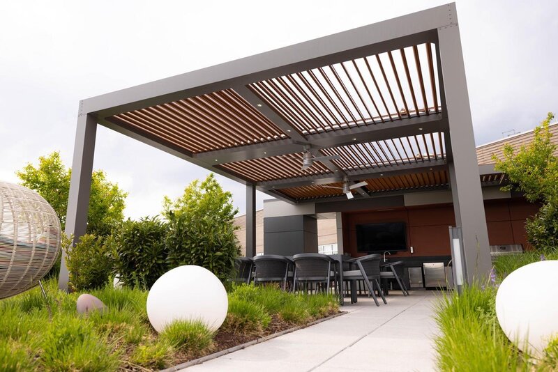 A large StruXure pergola with integrated fans and lights with furniture underneath. 