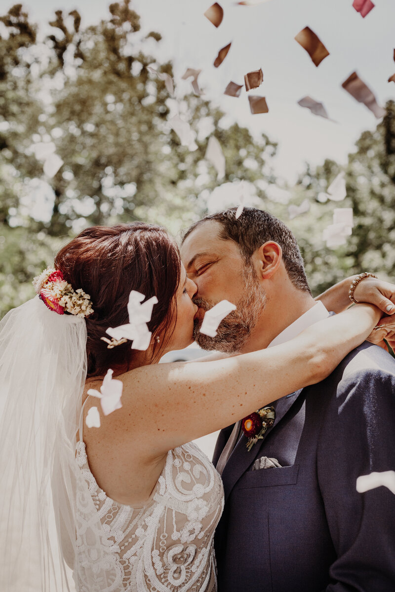 bride and groom kissing with confetti