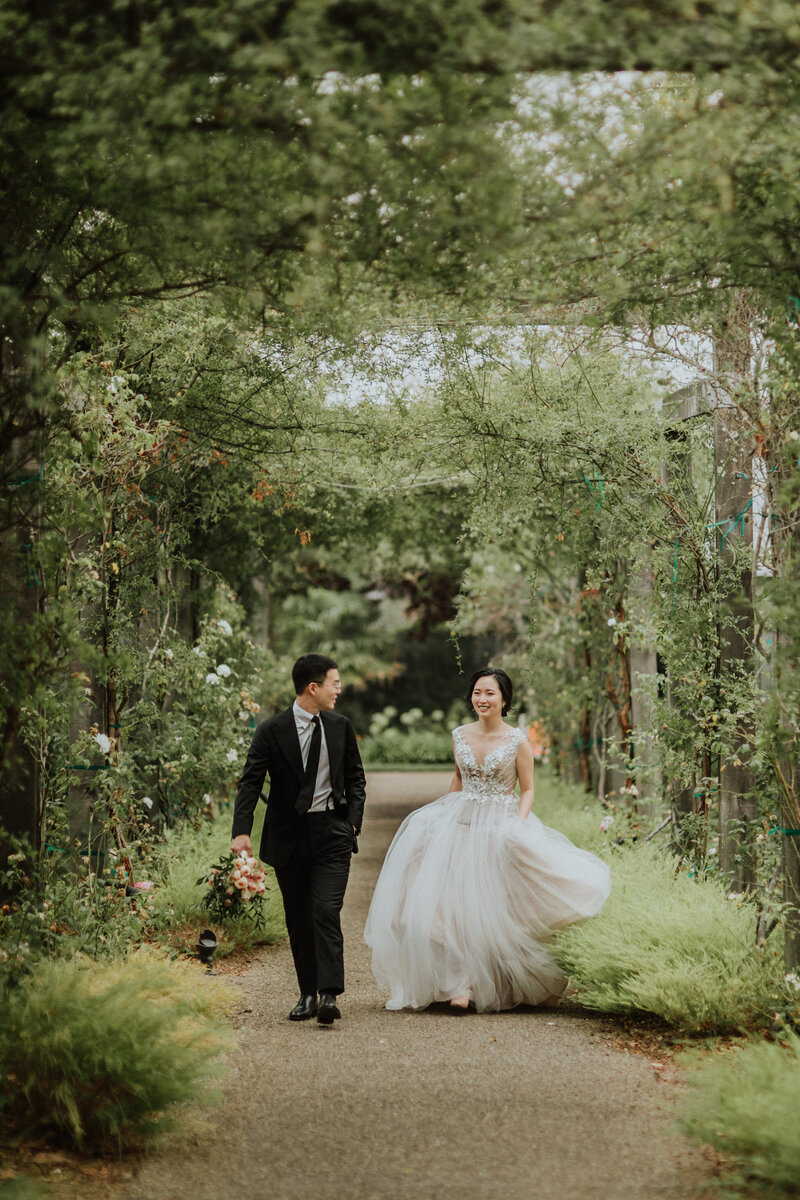 bride and groom walking through naturer