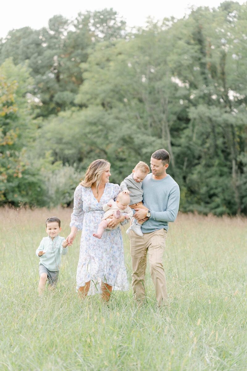 family of five walks through a field during a photo session with AnneMarie Hamant