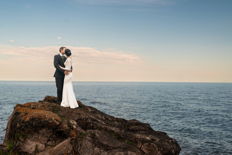 Bride and groom kiss at sunset in front of Lake Superior in Tofte, Minnesota.