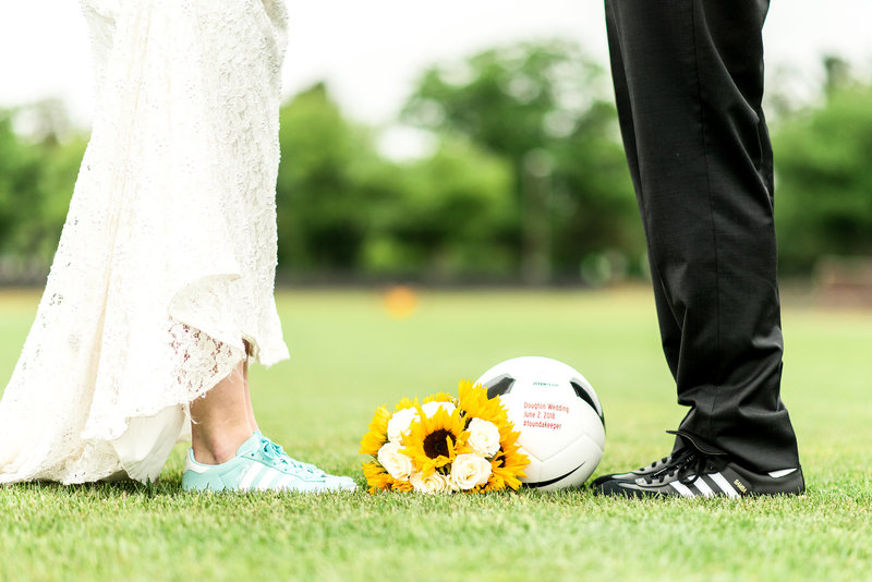 Bride and grooms feet with sunflower bouquet and soccer ball between them