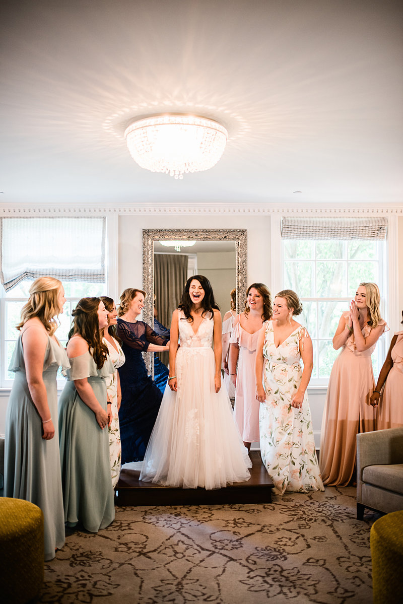 A bride laughing as she gets ready with her bridesmaids admiring her wedding dress at The Blaisdel in Minnesota