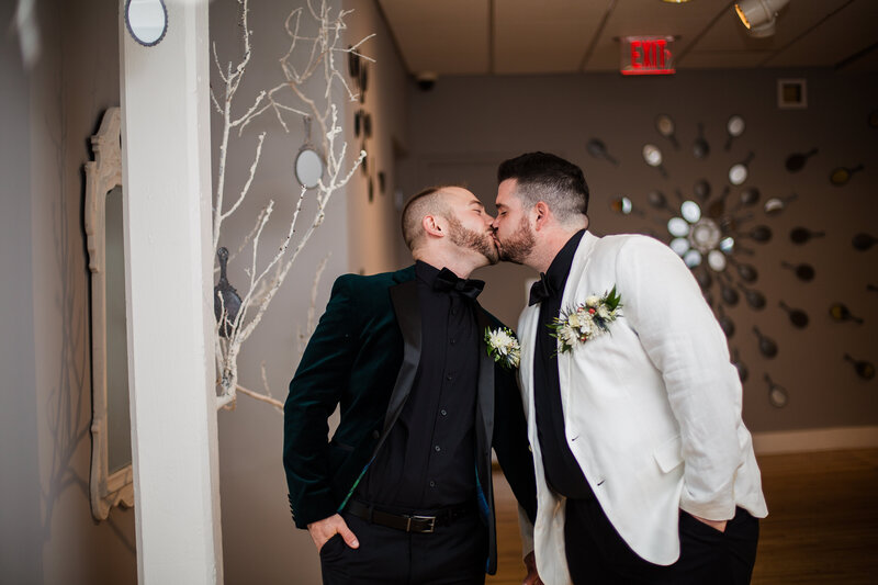 Grooms kiss while walking hand in hand through the halls of the Erie Art Museum