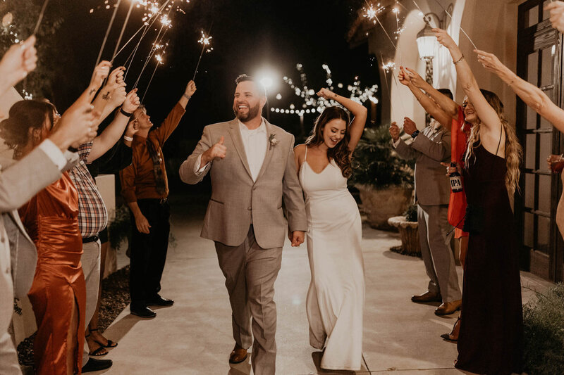 Bride and groom dancing down an aisle during their sparkler exit