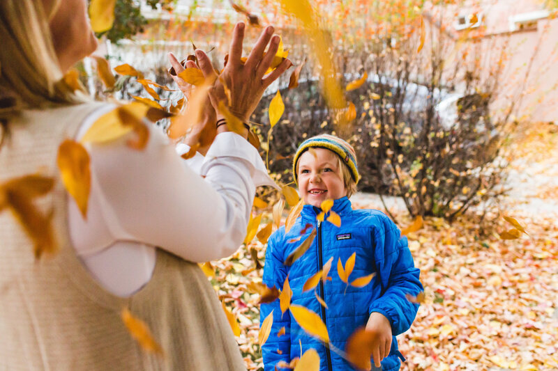 Son throwing leaves at mother during Denver Family Photo session in Park Hill neighborhood