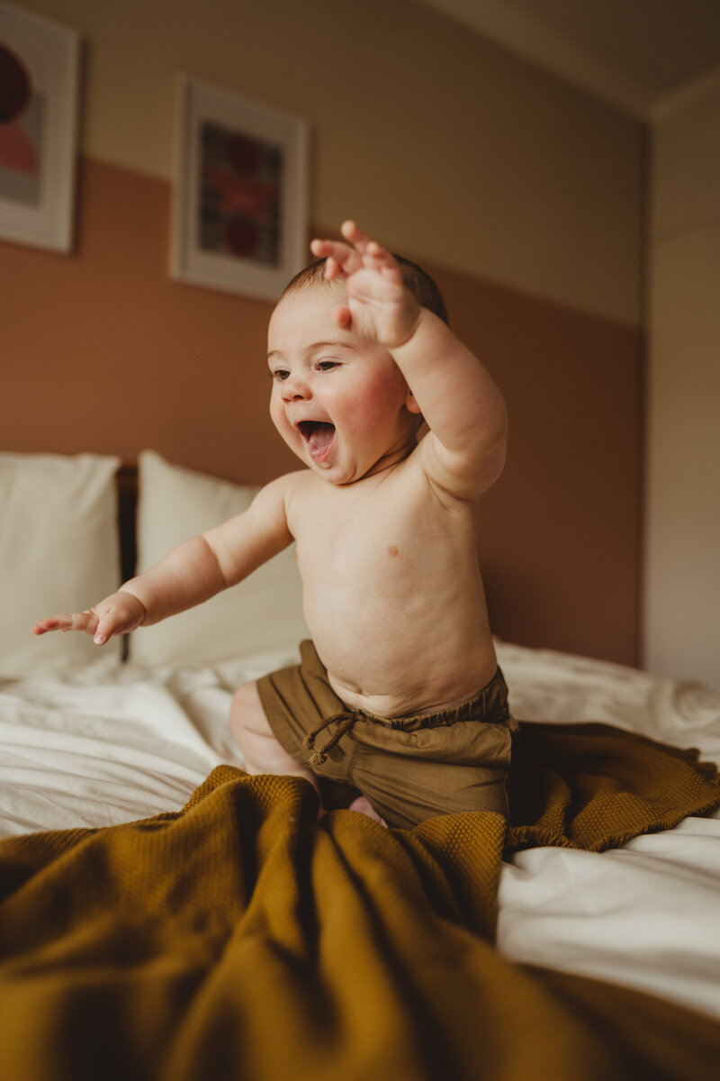 baby laughing jumping on bed
