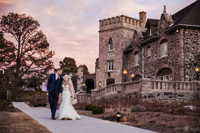 Couple walks down the main path at Highlands Ranch Mansion at Sunset on their winter wedding day